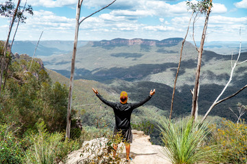 Man hiking Blue Mountains Australia. Dramatic views of valley, landscape, green rainforest jungle. Adventure, freedom, fun concepts. Tourist mountain trek. Shot in Sydney, NSW