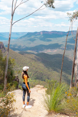 Woman hiking Blue Mountains Australia. Dramatic views of valley, landscape, green rainforest jungle. Adventure, freedom, fun concepts. Tourist mountain trek. Shot in Sydney, NSW.
