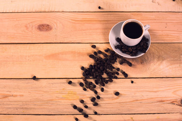 Coffee cup on coffee beans in wooden background