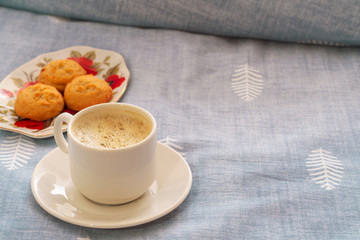 a cup of strong coffee and cookies. breakfast in bed. cup of coffee and cookies on textile blue background