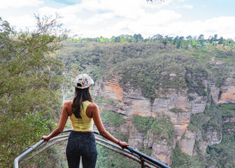 Woman hiking Blue Mountains Australia. Dramatic views of valley, landscape, green rainforest jungle. Adventure, freedom, fun concepts. Tourist mountain trek. Shot in Sydney, NSW.