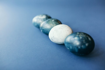 Beautiful group ombre blue Easter eggs with quail eggs and feathers on a blue background. Easter concept. Border eggs. Copy space for text.