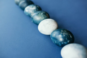 Beautiful group ombre blue Easter eggs with quail eggs and feathers on a blue background. Easter concept. Border eggs. Copy space for text.