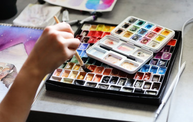 The process of drawing watercolors and near a large set of watercolor paints