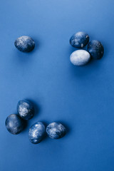 Beautiful group ombre blue Easter eggs with quail eggs and feathers on a blue background. Easter concept. Border eggs. Copy space for text.