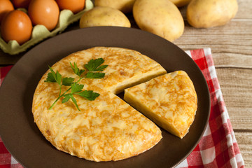 Spanish omelette and portion on wood