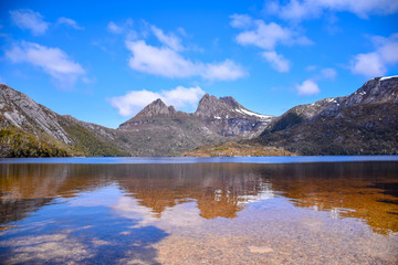 Fototapeta na wymiar The grass field with lake, snow mountain and cloudy blue sky background in Tasmania, Australia