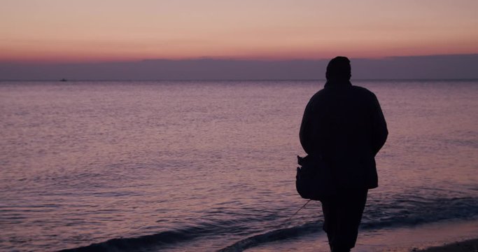 Rear view male fisherman surf fishing seashore sunrise, Mojacar, Almeria, Spain