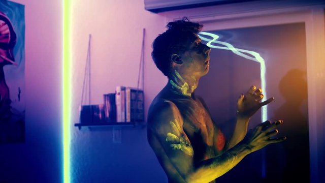 Man plays air sax in his apartment, while sporting eccentric body paint. Medium field of view, tripod.