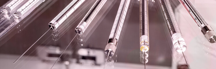 Close-up of glass syringe on light background. Monochrome toned image.