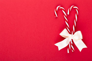 Christmas candy canes, stick and decor on color background. Christmas candy cane heart on an red background.