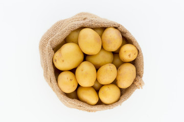 Sack of fresh raw potatoes on wooden background, top view