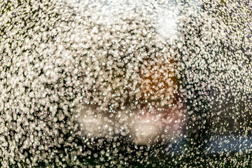 Abstract splashes of water on bokeh background in sunshine. Freeze motion of white particles. Rain, snow overlay texture.