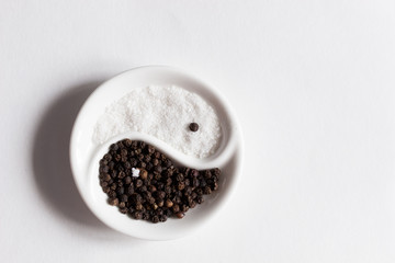 Salt and pepper in Yin Yang shaped bowl on white background