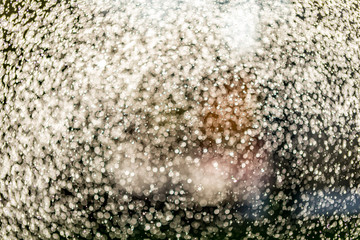 Abstract splashes of water on bokeh background in sunshine. Freeze motion of white particles. Rain, snow overlay texture.