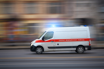 Ambulance van racing through city street with motion blur. First response vehicles car with flashing lights, special vehicle of paramedic emergency - inscription ambulance