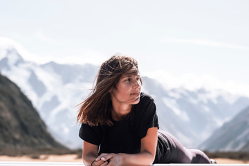 A young female traveler with green eyes lays down on top of her car. Copyspace