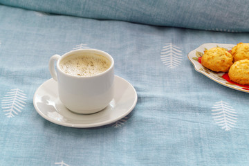 cup of coffee on a saucer and cookies in bed on a blue textile background