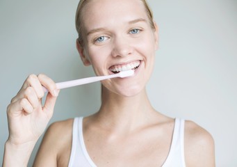 Beautiful blonde woman brushing her teeth. Attractive model brushing her teeth and smiling. teeth whitening dentist. 