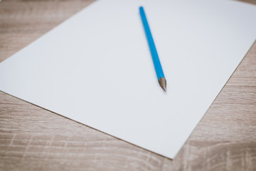 Blank white paper with a pencil on a wooden table.