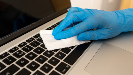 
A woman disinfects a computer with an antiseptic wet wipe. Antiseptic wipe to prevent the spread of germs, bacteria and coronavirus. Coronavirus Prevention. Prevention of coronavirus disease after a 