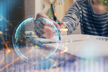 Double exposure of hands making notes with world map hologram and data theme icons. Concept of...