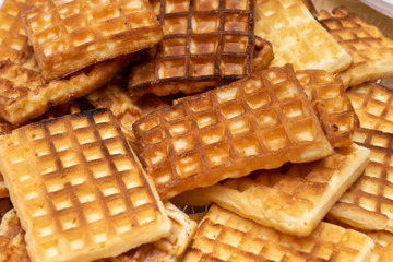 Heap of golden homemade Belgian Waffles on a plate close up for breakfast or a snack.