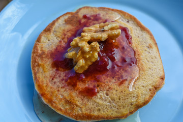 Pancakes with maple syrup, walnuts and red fruit jam.