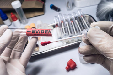 Criminological police officer cuts with scissors hyssop with blood sample to be analyzed in laboratory, conceptual image