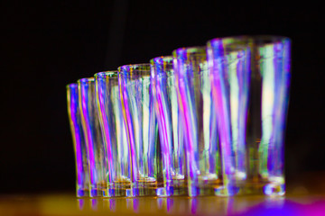 A glass of water arranged in a row on a table with a black background.