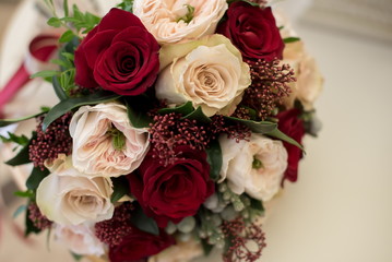 Bridal bouquet of red and cream roses, eustoma and ornamental plants
