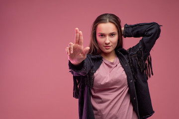 cheerful girl in a fringed jacket dances on a pink background.