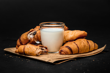 Croissants with milk on newsprint on a black background