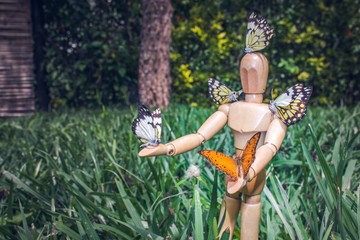 
Wooden Human Manikin posing with an orange Butterfly sitting on a leaf resting, South Africa
