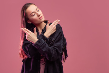 cheerful girl in a fringed jacket dances on a pink background.