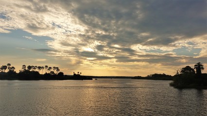 Sunset on the Zambezi River. The expanse of the river, low clouds, tree silhouettes and the sun...