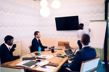 Multiethnic colleagues watching woman making presentation