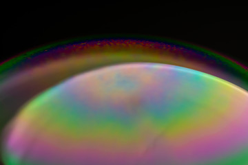 Psychedelic abstract planet from soap bubble, Light refraction on a soap bubble, Macro Close Up in soap bubble. Rainbow colors on a black background. Model of Space or planets universe cosmic galaxy.