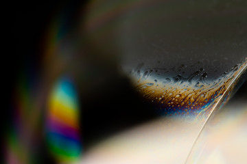 Psychedelic abstract planet from soap bubble, Light refraction on a soap bubble, Macro Close Up in soap bubble. Rainbow colors on a black background. Model of Space or planets universe cosmic galaxy.