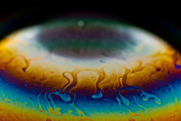 Psychedelic abstract planet from soap bubble, Light refraction on a soap bubble, Macro Close Up in soap bubble. Rainbow colors on a black background. Model of Space or planets universe cosmic galaxy.