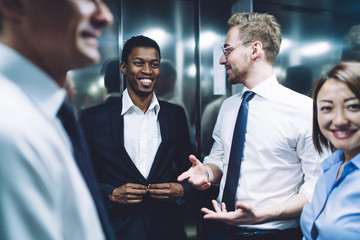 Diverse happy team of colleagues communicating in elevator
