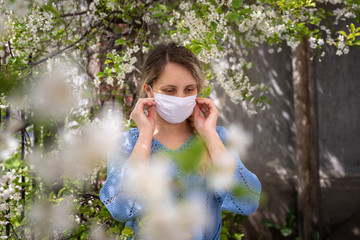 Young beautiful woman in a protective medical mask. close-up portrait. spring, against the backdrop...