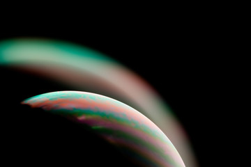 Psychedelic abstract planet from soap bubble, Light refraction on a soap bubble, Macro Close Up in soap bubble. Rainbow colors on a black background. Model of Space or planets universe cosmic galaxy.