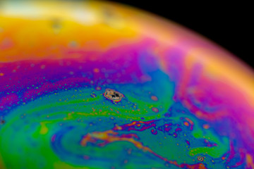 Psychedelic abstract planet from soap bubble, Light refraction on a soap bubble, Macro Close Up in soap bubble. Rainbow colors on a black background. Model of Space or planets universe cosmic galaxy.