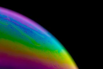 Psychedelic abstract planet from soap bubble, Light refraction on a soap bubble, Macro Close Up in soap bubble. Rainbow colors on a black background. Model of Space or planets universe cosmic galaxy.
