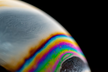 Psychedelic abstract planet from soap bubble, Light refraction on a soap bubble, Macro Close Up in soap bubble. Rainbow colors on a black background. Model of Space or planets universe cosmic galaxy.