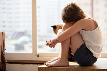 The child looks out the window. Quarantined self-isolation boy