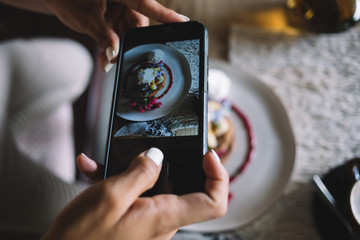 Woman shooting with smartphone well plated and garnished dessert in cafe