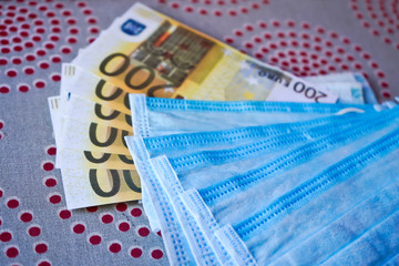 Obraz premium Medical masks with money. European money with protective masks. Fan EURO with a fan of medical masks.