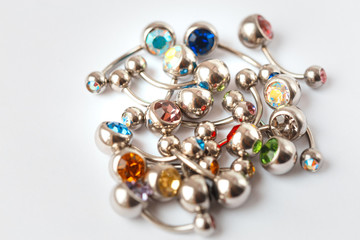 A mix of different multicolored navel piercing earrings - red, orange, yellow, green, blue, indigo blue and purple. Macro closeup